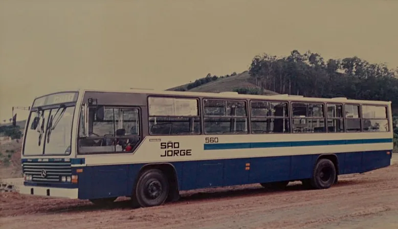 Ônibus antigo da São Jorge, número 560, parado em estrada de terra com morros ao fundo.