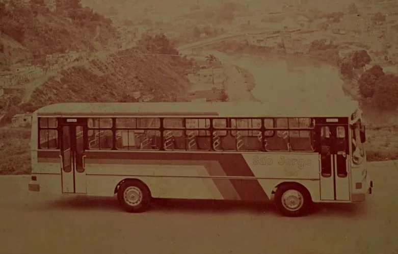 Ônibus antigo da São Jorge visto de lado, em área rural.